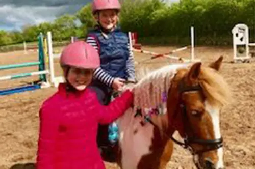 2 kids smiling while riding a horse in County Antrim