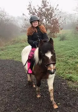 Smiling ginger girl with pink boots on small horse in County Antrim