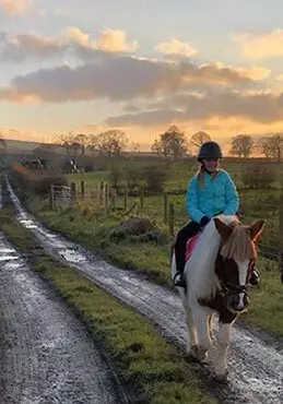 Young girl riding Dolly with sun setting in the background in County Antrim