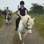 Young girl in black on white horse in County Antrim